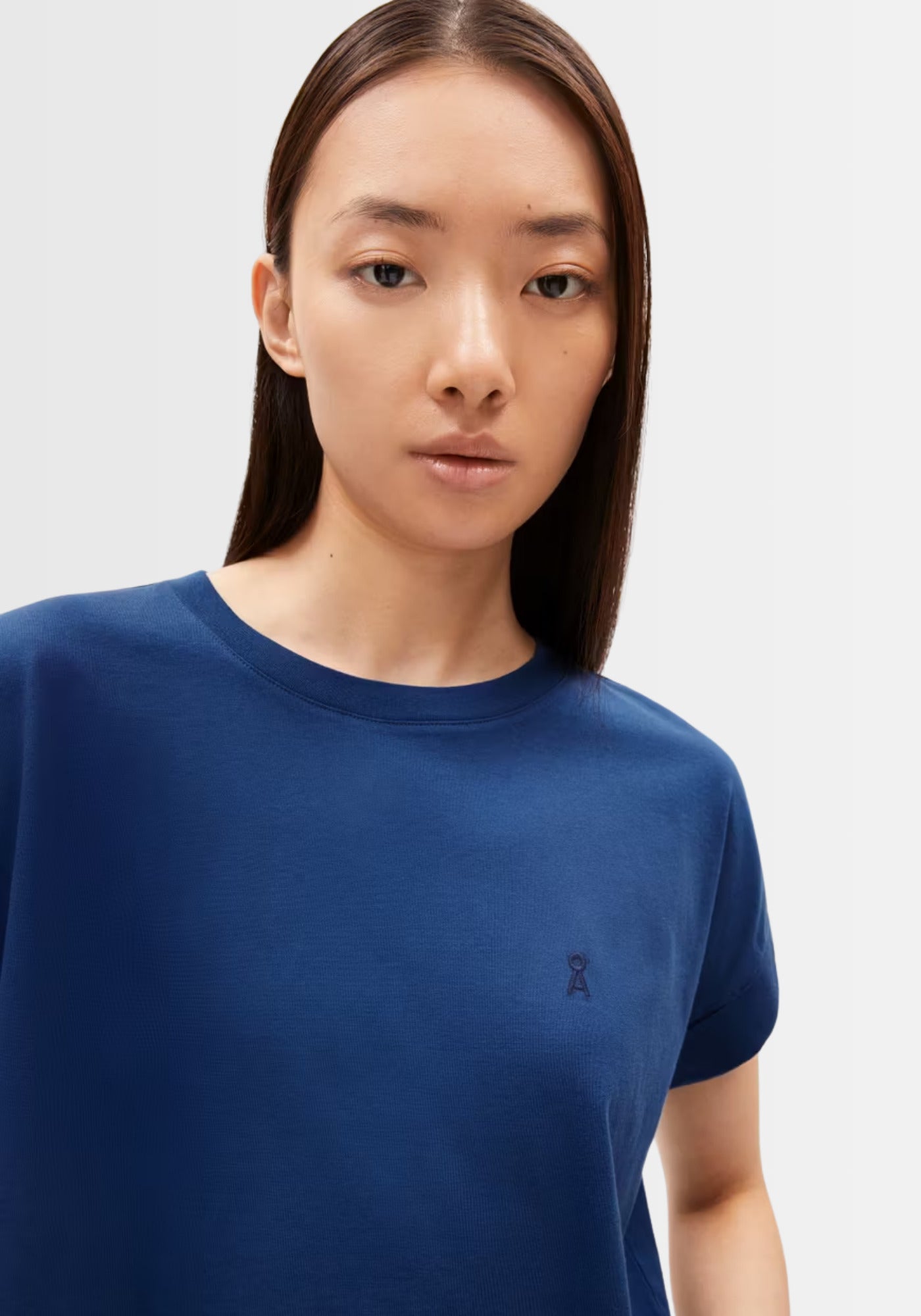 Nahaufnahme des dunkelblauen IDAARA T-Shirts aus weicher Bio-Baumwolle, mit kleinem, gesticktem Logo und rundem Halsausschnitt.