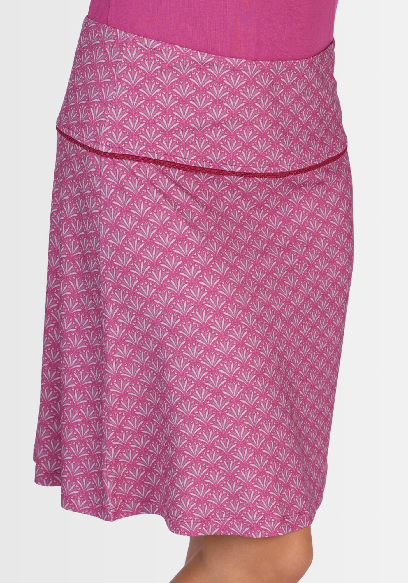 Seitenansicht des A-Linien-Rocks „Amanda“ in Raspberry mit dezentem Federprint. Durch das breite Bündchen und die anschmiegsame Viskose-Elasthan-Qualität kommt die weibliche Silhouette perfekt zur Geltung.