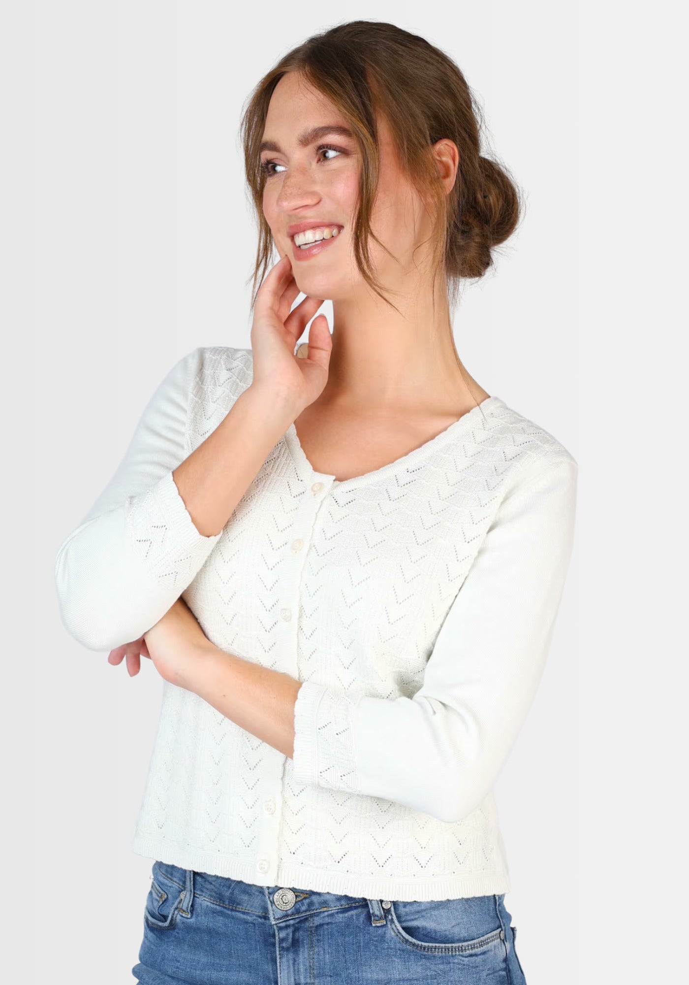 Seitenansicht der „Liselotte“ Strickjacke in Weiß. Der weiche Stoff aus Bio-Baumwolle zeigt ein zartes Ajourmuster und die präzise gearbeitete Knopfleiste, die den femininen Look unterstreicht.