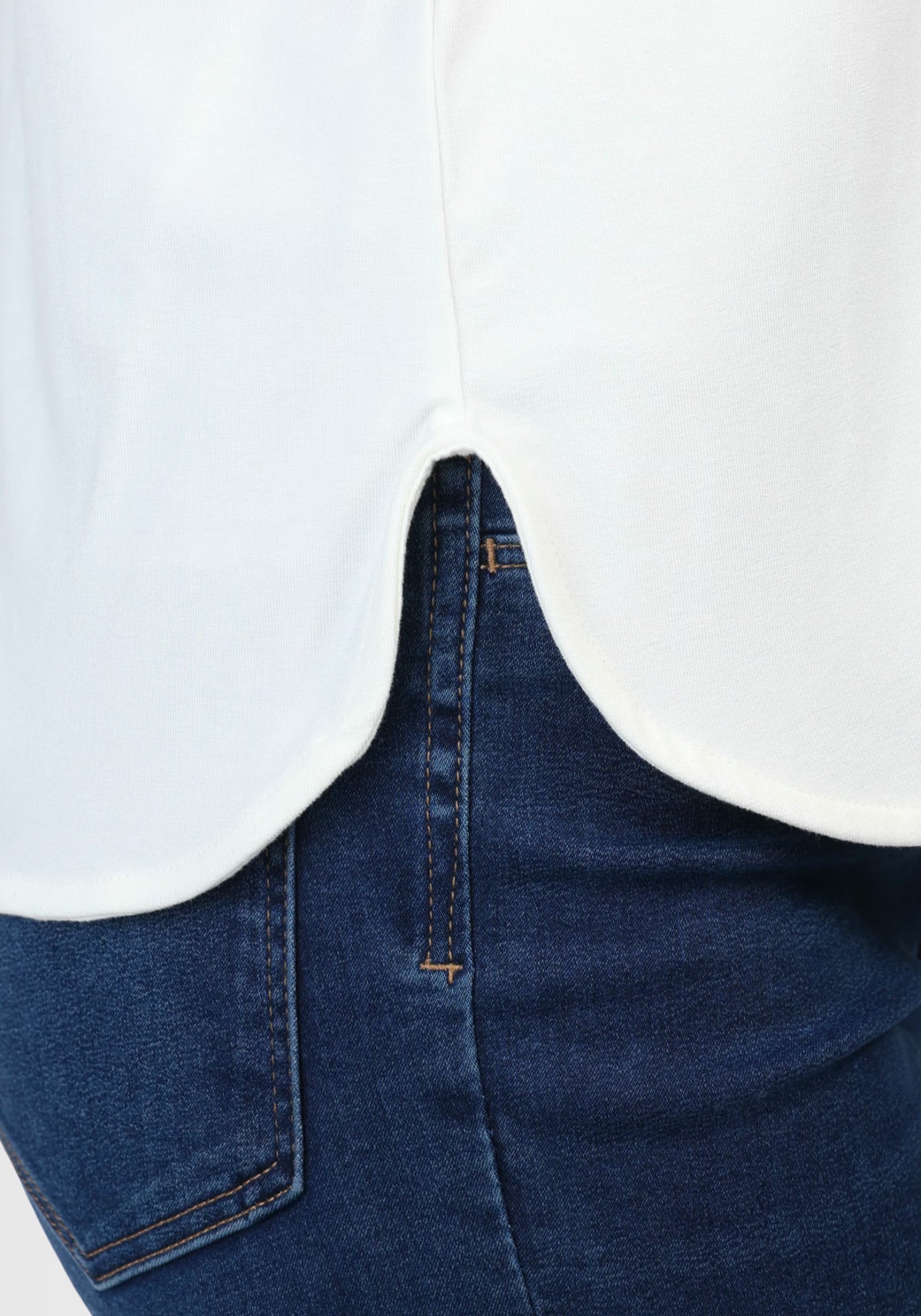 Detailaufnahme des seitlichen Schlitzes am Saum des „Betzi“ T-Shirts in Elfenbeinweiß, der für zusätzliche Bewegungsfreiheit und eine schmeichelnde Silhouette sorgt.