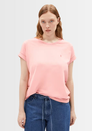 Model zeigt den femininen Rundhalsausschnitt und das dezente Logo des Idaara T-Shirts in zartem Rosaton, ideal für einen entspannten Alltagslook.