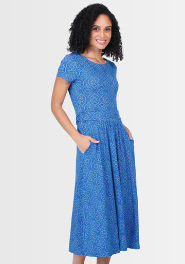 Seitenansicht des eleganten Midikleids „Malind mandala“ in Lapis. Die lässigen Eingrifftaschen und der fließende Rock mit charmanten Raffungen unterstreichen die bequeme, zugleich feminine Silhouette.
