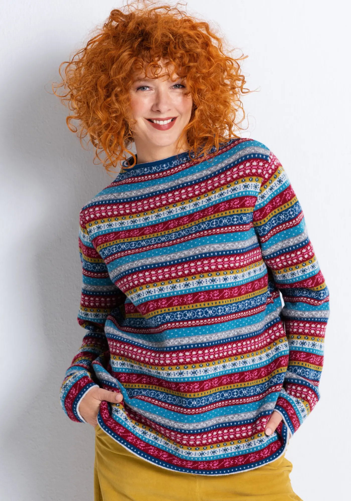 Smilla Strickpullover in bunten Farben, getragen von einem Model. Der Pullover ist aus 100% Schurwolle gefertigt und bietet eine bequeme Passform.